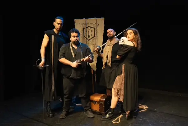 Tres actores en el escenario, riendo y gesticulando, en una obra de improvisación teatral con temática shakesperiana.